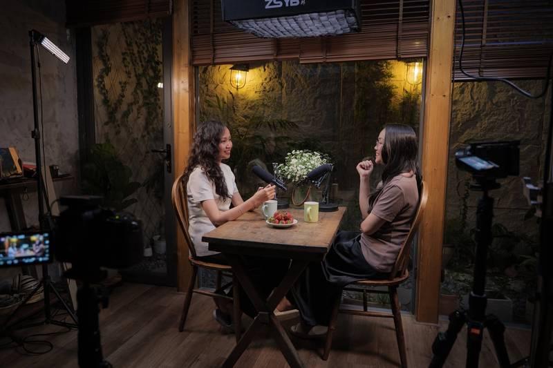 Hai phụ nữ đang trò chuyện trong buổi thu âm với thiết bị hiện đại, minh họa cho dịch vụ quay video podcast trọn gói.