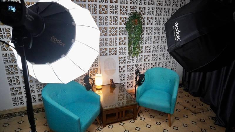 Ảnh phòng quay với ánh sáng chuyên nghiệp và ghế sofa xanh dùng trong dịch vụ quay video podcast trọn gói.