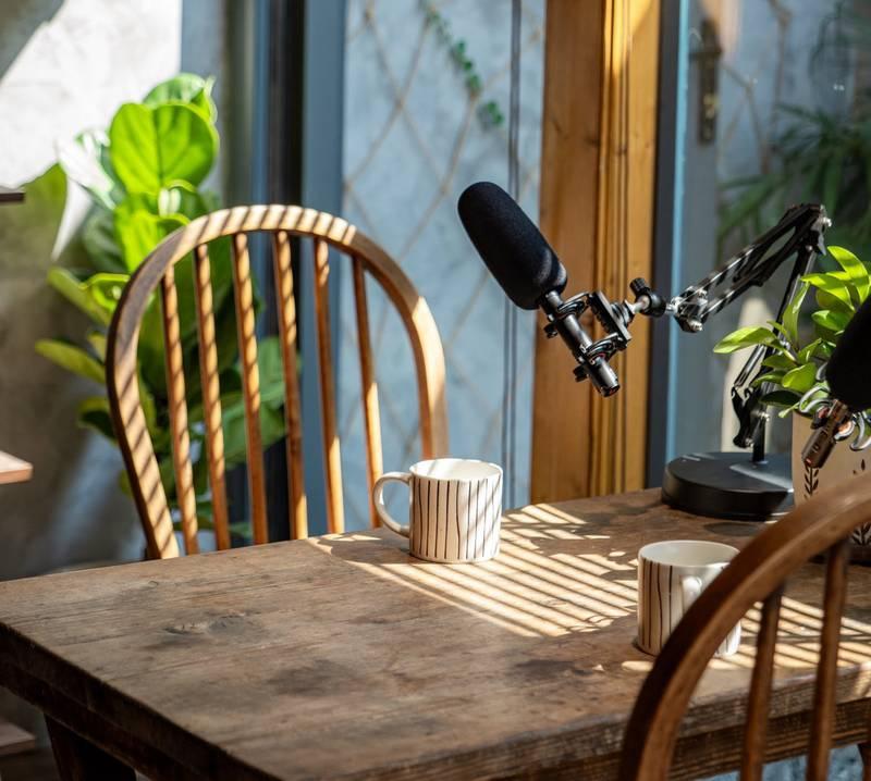 Bàn quay podcast với micro và ly cà phê trong không gian ấm cúng cho dịch vụ quay video podcast trọn gói.